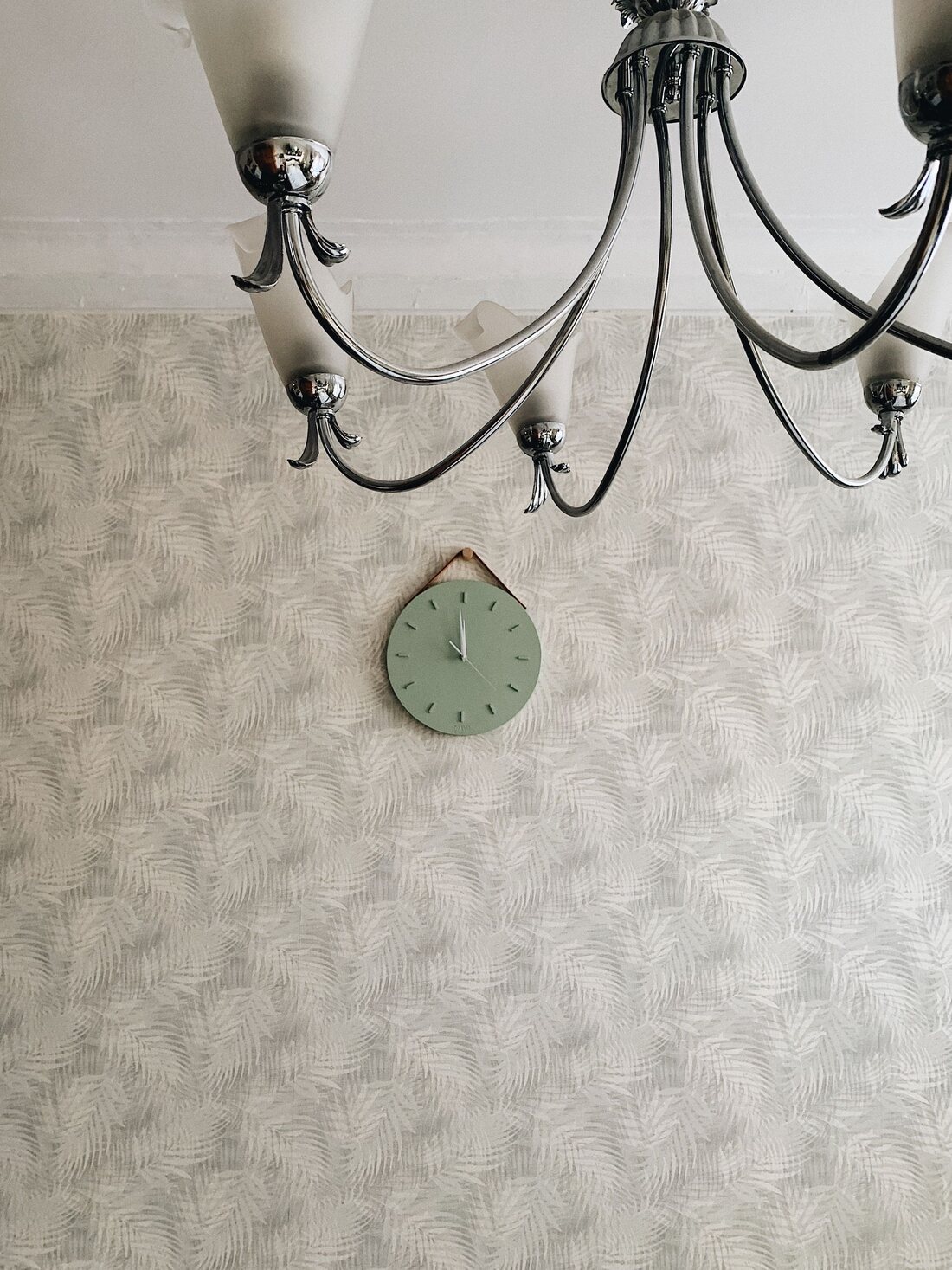 Room with textured grasscloth-style leaf-pattern wallpaper and a black chandelier